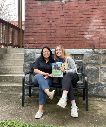 Denica Obis and Kayla Valente posing with a copy of  “Healthy Home Lab Age- Friendly Garden Toolkits and Case studies” handbook they created