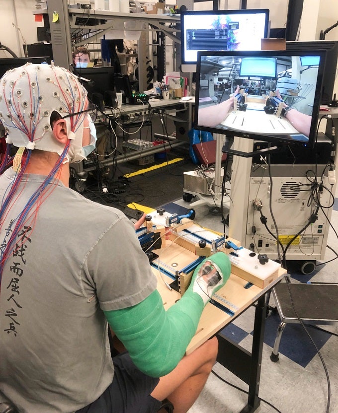 A participant in Proessl's PhD research performing mental imagery while wearing the electroencephalography cap and the cast. 