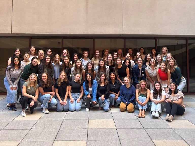 Group of students standing together in an atrium.