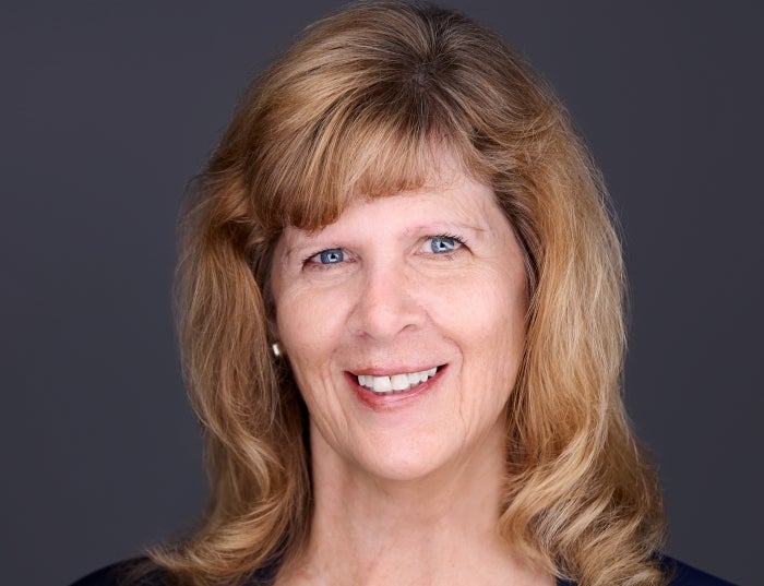 Woman with auburn blonde hair in front of a dark gray background.