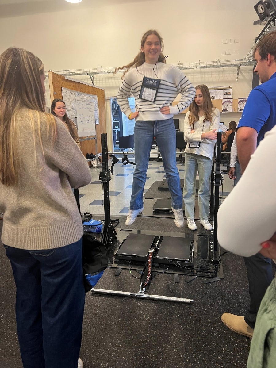 A young woman leaps on testing equipment called force plates