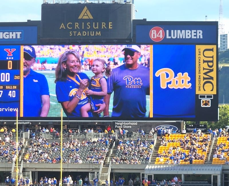 Toto being recognized on the field for her award with her granddaughter during the Pitt football homecoming game 