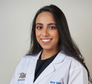 Woman with long dark hair wearing a white lab coat over a black shirt.