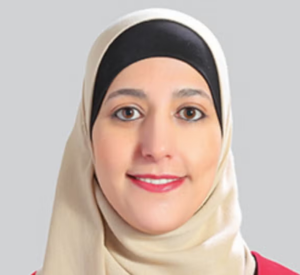 Woman wearing a tan hijab and a red sweater.