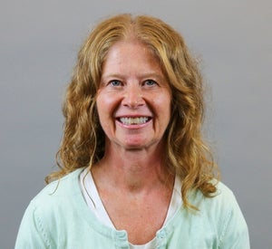 Woman with strawberry blonde hair wearing a pastel green cardigan over a white top.