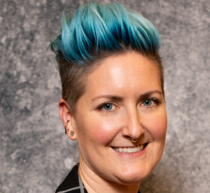 Woman with dark hair dyed blue hair wearing a dark collared shirt.