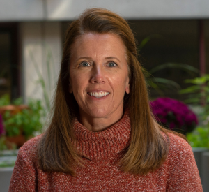 Woman with auburn hair wearing a red sweater.