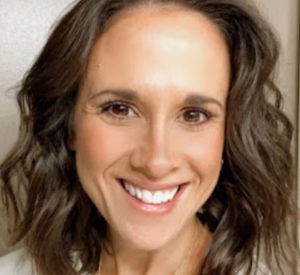 Woman with dark brown hair wearing a white shirt.