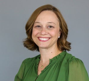 Woman with short auburn hair wearing a lime green blouse and a gold necklace.