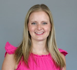 Woman with blonde hair wearing a bright pink blouse.