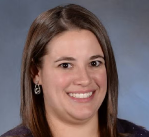 Woman with short brown hair wearing a dark brown sweater.