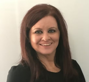 Woman with dark red hair wearing a black blouse.