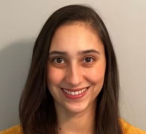 A woman with brown hair wearing an orange shirt.