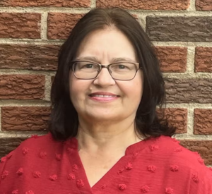 Woman with dark brown hair wearing a red blouse.