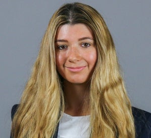 Woman with long blonde hair wearing a black blazer over a white top.