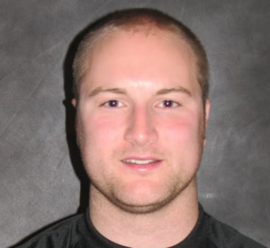 Man with very short blonde hair wearing a black shirt.