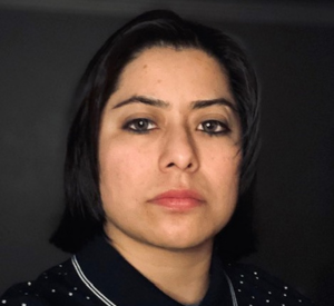 Woman with dark hair wearing a black polka dot shirt.