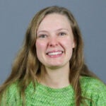 Woman with light brown hair wearing a bright green sweater.