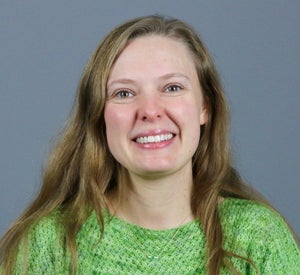 Woman with light brown hair wearing a bright green sweater.