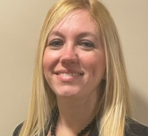 Woman with blonde hair wearing a dark brown shirt.