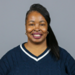 Woman with dark brown hair pulled to the side wearing a navy blue sweater with a white stripe at the neck.