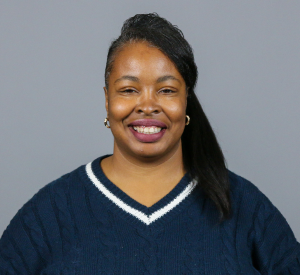 Woman with dark brown hair pulled to the side wearing a navy blue sweater with a white stripe at the neck.