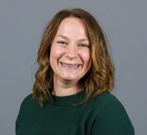 Woman with short brown hair wearing a dark green sweater.