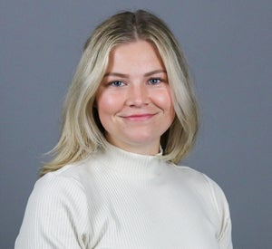 Woman with short blonde hair wearing a white turtleneck sweater.