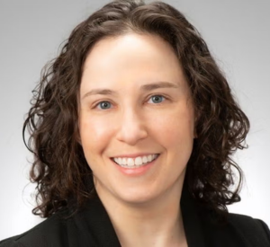 Woman with dark brown hair wearing a black blazer.