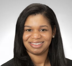 A woman with dark brown hair wearing a black blazer.