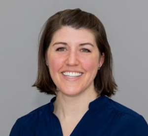 Woman with short brown hair wearing a navy blue blouse.