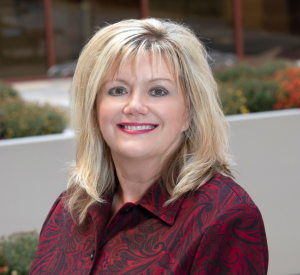 Woman with blonde hair wearing a red collared shirt with a paisley style print.