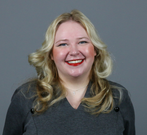 Woman with blonde hair wearing a dark gray dress.