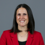 Woman with short black hair wearing a red blazer over a black top with a gold necklace.