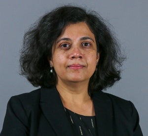 Woman with short black, wavy hair, wearing dangle earrings and a black blazer