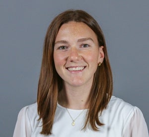 Woman with brown-red hair wearing a white top.