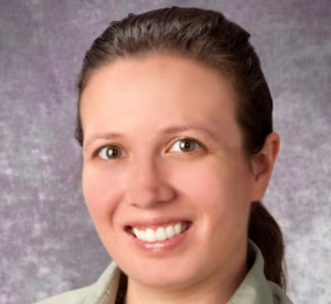 Woman with brown hair pulled back wearing a light green collared shirt.