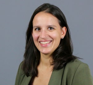 Woman with medium length, dark brown hair, wearing an army green blazer.