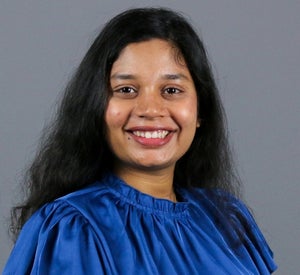 Woman with long black hair wearing a royal blue top.