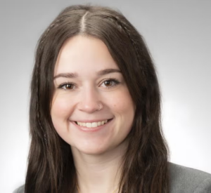 Woman with dark brown hair wearing a green blazer.