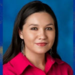 Woman with dark hair wearing a red collared shirt.