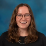 Woman with brown hair and glasses wearing a black shirt.