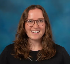 Woman with brown hair and glasses wearing a black shirt.