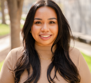 Woman with long dark hair wearing a tan turtleneck.