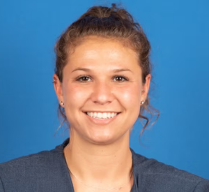 Woman with brown curly hair wearing a dark gray blazer.