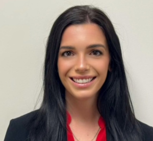 Woman with black hair wearing a black blazer over a red blouse.