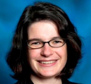 Woman with dark short hair and glasses wearing a dark shirt.