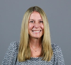 Woman with long blonde hair wearing a patterned navy and white shirt.