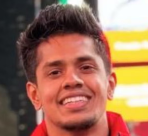 Man with dark hair wearing a red shirt.