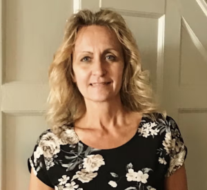 Woman with blonde hair wearing a black shirt with florals.